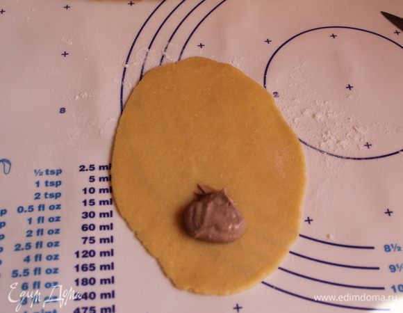 Теперь берем одну часть и раскатываем ее. На край лепешки кладем чайную ложку начинки.