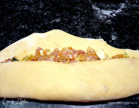 Заворачиваем передний и задний края теста и сворачиваем пласт рулетом, плотно прижимаем каждый сгиб и укладываем готовый рулет на припыленную мукой поверхность швом вниз. Режем на порционные кусочки. Укладываем на пищевую пленку так, чтобы между равиоли оставался промежуток и прикрываем полотенцем или пленкой.