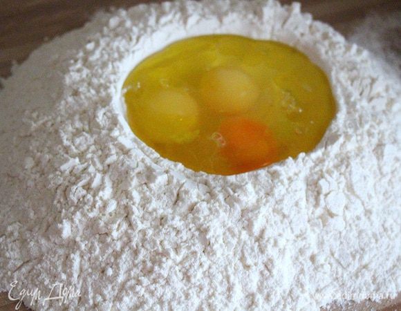 На рабочую поверхность насыпаем горкой муку, делаем в центре выемку и вбиваем туда яйца. Добавляем оливковое масло, пару столовых ложек. Важно: не солить тесто при замешивании, т. к. соль нейтрализует жиры яиц и муки. Оливковое масло, напротив, помогает сделать тесто более эластичным.