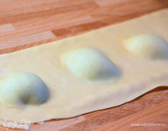 Накрываем ее верхней частью полосы, чтобы начинка была полностью накрыта. Проходимся пальцем по тесту, чтобы удалить воздух изнутри и скрепить края тортелли.