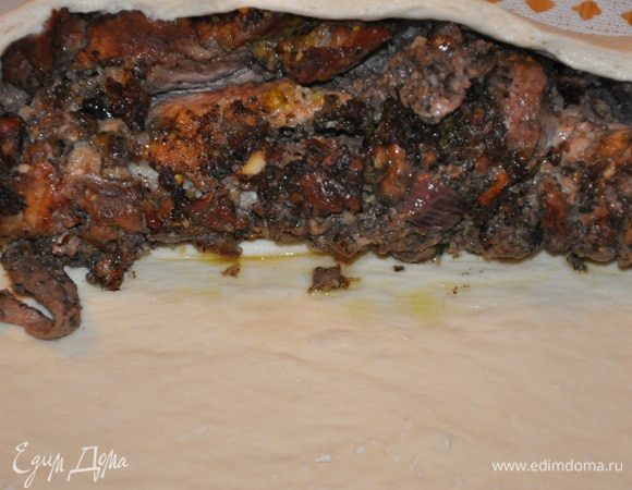 Теперь раскатываем наше тесто. Снимаем нитки с рулета и кладем его на тесто, плотно заворачиваем и надрезаем ножом.