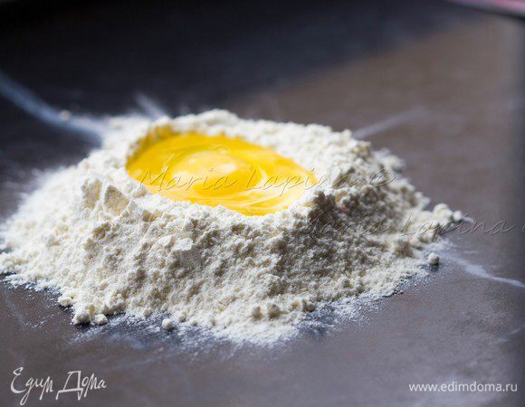 Насыпать горку муки, сделать в ней воронку и разбить туда яйцо. 