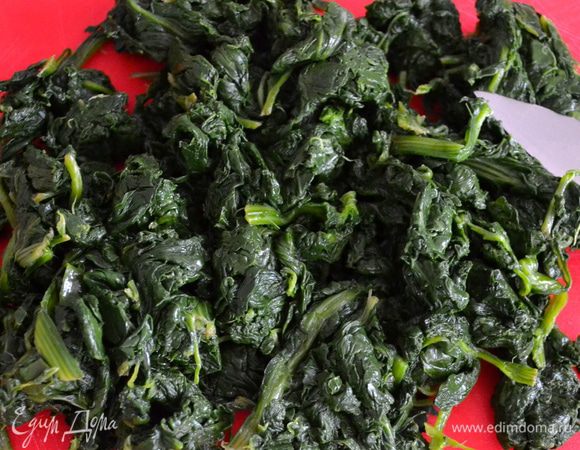 Приготовить шпинат. Листья шпината хорошо вымыть, стряхнуть лишнюю жидкость и положить на сухую сковороду с антипригарным покрытием (жидкости, что осталась на листьях будет вполне достаточно!) и на среднем огне дать ему уменьшится в объеме, потемнеть... Готовый шпинат отжать от лишней влаги и мелко порубить ножом.