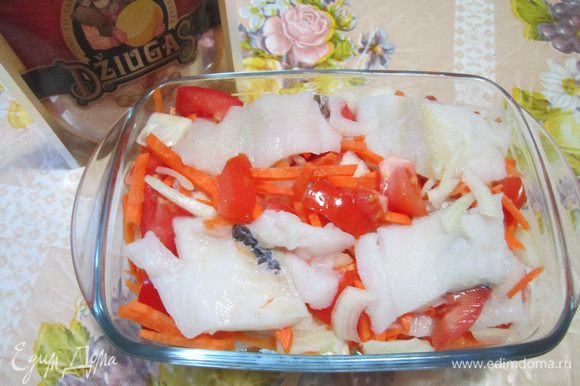 Растительное масло разогреть в форме для запекания и уложить в неё нарезанную подсоленную рыбу. Кусочки рыбы переложить дольками помидоров, лука и моркови. Тушить рыбу в духовке 20-30 минут в зависимости от духовки.