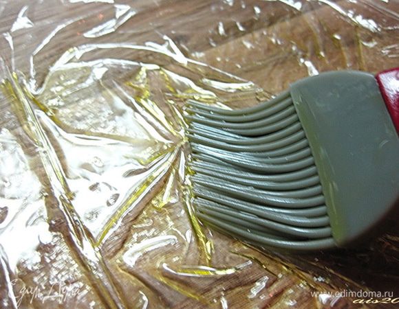 Нам понадобится пищевая пленка, на каждое яйцо нужно отрезать прямоугольный кусочек пленки (приблизительно 15х15 см). Пленку разложить на доске и смазать оливковым маслом.