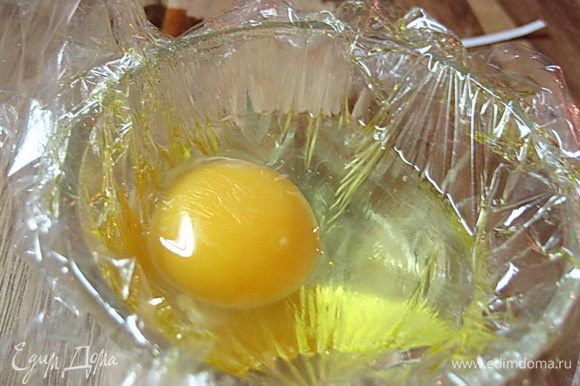 Пленку выложить на небольшую пиалу, в углубление вылить яйцо. По желанию можно сразу посолить или оставить право выбора едоку за столом.