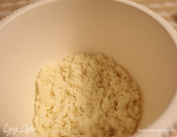 Вторую половину сахара смешать с кокосовой стружкой. Добавить смесь к яйцу и хорошо перемешать. Получится рассыпчатая, но пластичная масса. Разогреть духовку до 170 градусов.