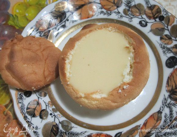 Со стороны плоской поверхности вырезать аккуратно «шапочку» (сохранить её). Наполнить заварным кремом и закрыть шапочкой. Сделать пропитку. Смешать свежевыжатый апельсиновый сок с сахаром. Вскипятить и остудить. Очень быстро опустить пирожные выпуклой стороной в сироп и перевернуть донышком вниз. Поставить в холодильник на 1-2 часа. 
