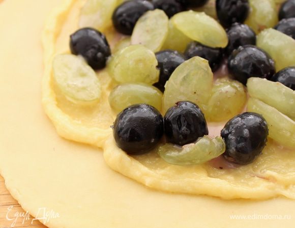 На середину пласта из теста выложить 1/2 часть миндального крема, оставляя от края сантиметра 3-4. Поверх крема - начинку из винограда.