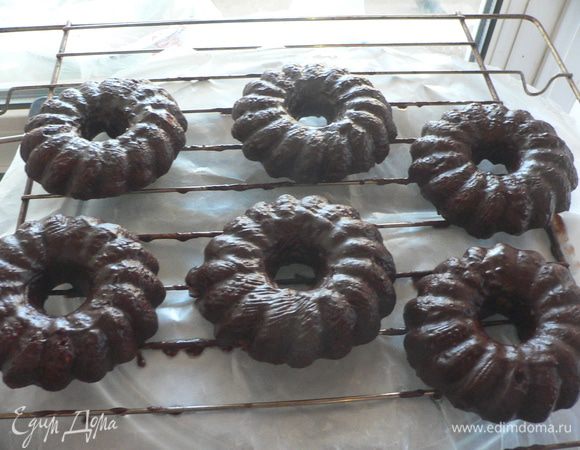 Для шоколадной глазури сложить шоколад в огнеупорную миску, добавить молоко и нарезанное кубиками масло. Поставить на водяную баню и нагревать, пока шоколад и масло не начнут плавиться. Размешать, чтобы получилась однородная масса. Переставить решетку с остывшими кофейными кольцами на противень или большую форму, чтобы собирать стекающую глазурь. Намазать кисточкой шоколадную глазурь на изделия по всей поверхности. Оставить на час. 