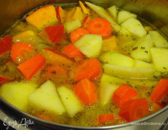 В кастрюлю погружаем тыкву, яблоко, морковь, обжаренный лук и заливаем овощным бульоном. Слегка подсаливаем.