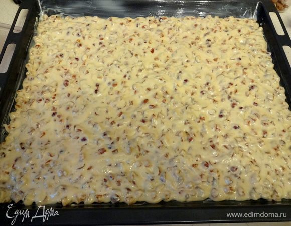 На смазанный сливочным маслом противень выложить тесто и равномерно его распределить по всей поверхности. Если не удается сделать это лопаточкой, можно разровнять тесто смоченной в воде рукой.