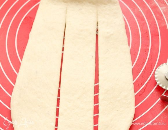 Один батон скалкой раскатайте в лепёшку, немного оставив у основания. Лепёшку разрежьте на 3 полоски.