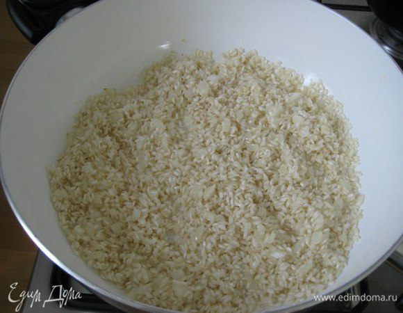 В отдельную сковородку положить масло сливочное, добавить мелко порезанный лук, обжарить лук до прозрачности, добавить рис, перемешать и добавить белое вино.