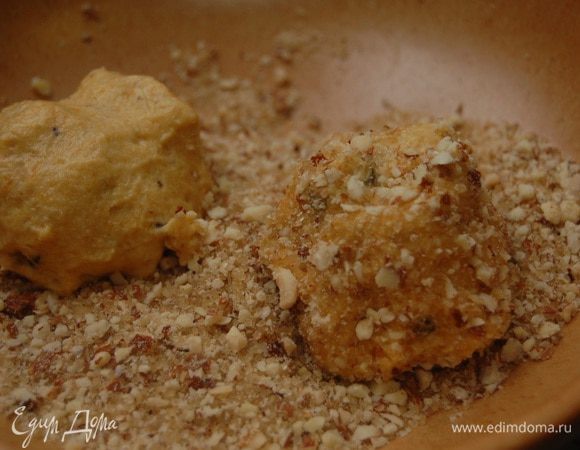 Мокрыми руками сформировать  шарики (вес каждого около 60 г), обвалять в ореховой крошке, выложить на пекарскую бумагу и слегка придавить рукой, придав форму лепешки.