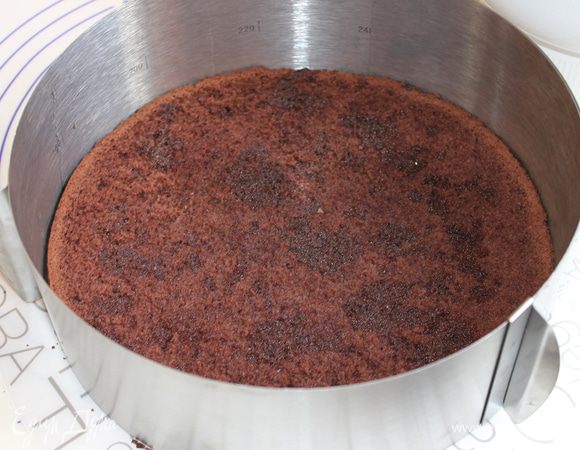 Собираем наш торт. Я взяла кольцо, но можно и без него. Кладем на блюдо темный корж. Можно пропитать сиропом, хотя сам бисквит получается очень нежным.