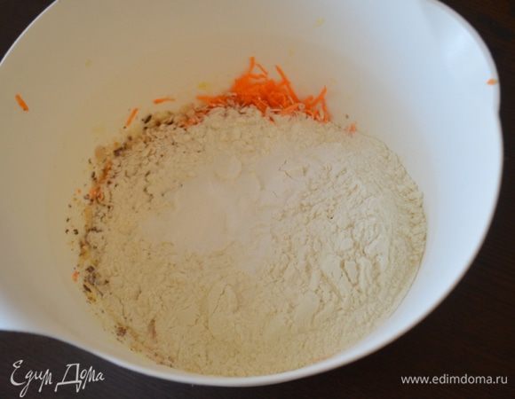 К яйцам добавить орехи, морковь, цедру апельсина, хлопья, пряности и соль. Просеять муку с разрыхлителем. Все перемешать.