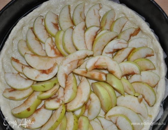 На тесто равномерно распределить ломтики яблок, посыпать сахаром,