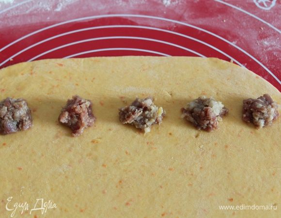Раскатать тесто в пласт, выложить небольшие кусочки фарша, отступив от края.