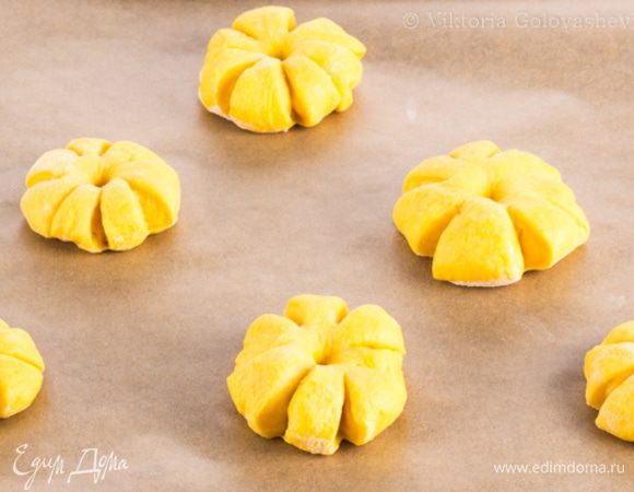 Сделайте надрезы по краю булочек, не доходя до центра. Середину вдавите пальцем. Уложите заготовки на противень (если не поместятся — то на несколько) на достаточном расстоянии друг от друга.