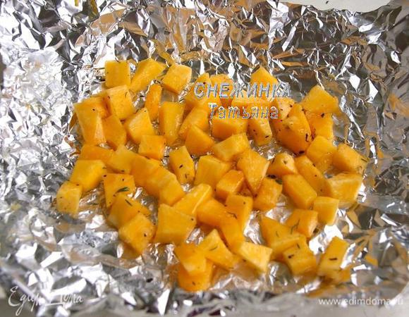 Тыкву нарезаем кубиком, в миске соединяем тыкву с растительным маслом, солью, перцем, тимьяном, базиликом, перемешиваем и выкладываем на фольгу. 
