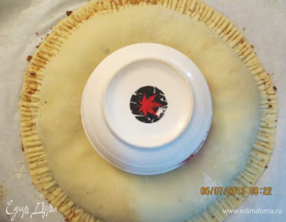 В центр положить маленькую чашку, нажав немного на лепешку.Зубцами вилки залепить края.
