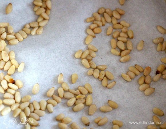 Разъемную форму выстилаем бумагой для выпечки. Насыпаем на неё кедровые орешки.