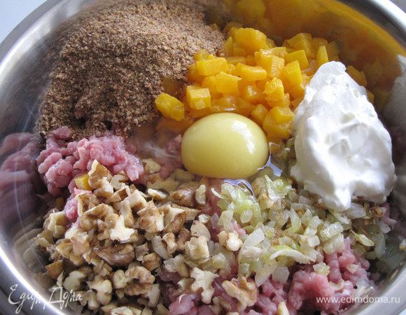 К мясному фаршу добавьте жареный лук с чесноком, тыкву, орехи, панировочные сухари, сметану, яйцо. Посолите и поперчите. Хорошо перемешайте.