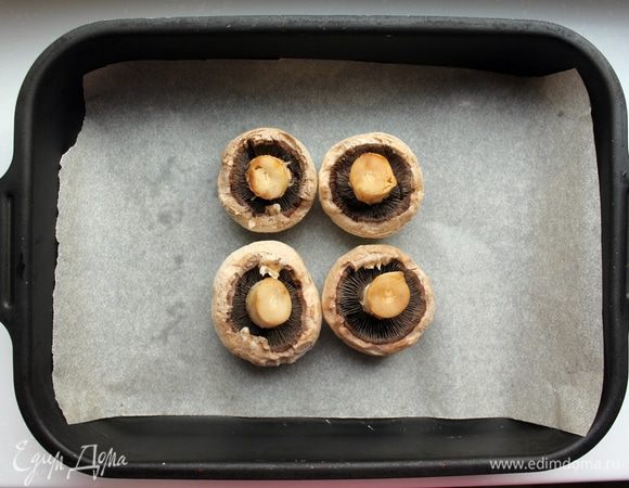 Грибы помыть, снять верхний слой. На поднос с бумагой для выпечки выложить грибы шляпками вниз.

