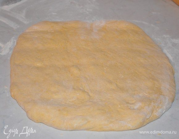 Теперь поднявшееся тесто раскатать на присыпанной мукой рабочей поверхности в пласт толщиной 1,5 см., вырезать кружочки небольшого диаметра (у меня был обычный стакан для сока),