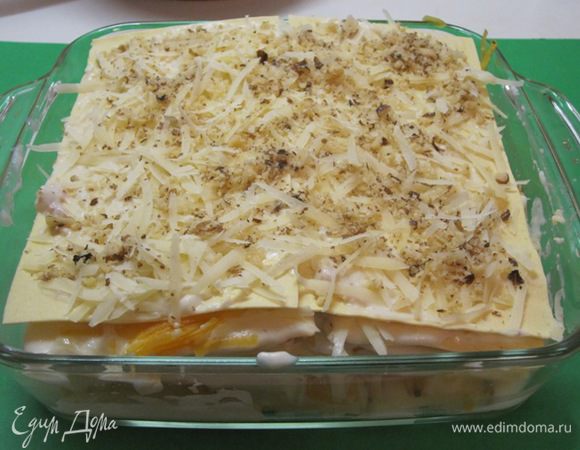 Верхний слой лазаньи полить соусом, посыпать тертым сыром и орехами.