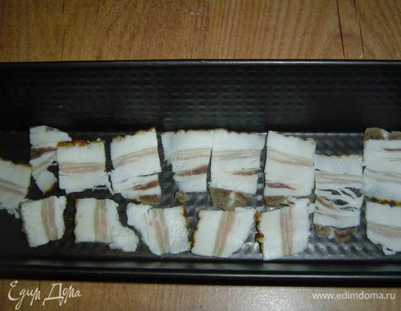 На дно формы выкладываем тонко нарезанный бекон,