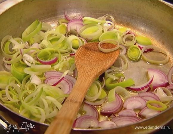 Разогреть в сковороде 1 ст. ложку оливкового масла, выложить нарезанный порей и красный лук, перемешать и обжаривать до прозрачности. 