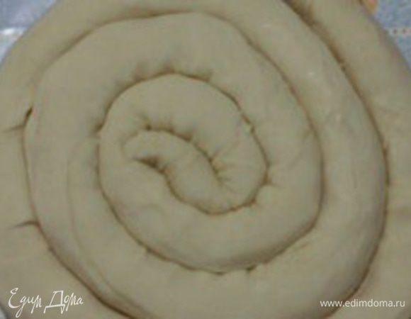 Скатать тесто в рулет, затем свернуть его в улитку и оставить, прикрыв полотенцем.