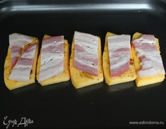 Затем разложите ломтики тыквы на смазанный оливковым маслом противень и укройте их ломтиками бекона.