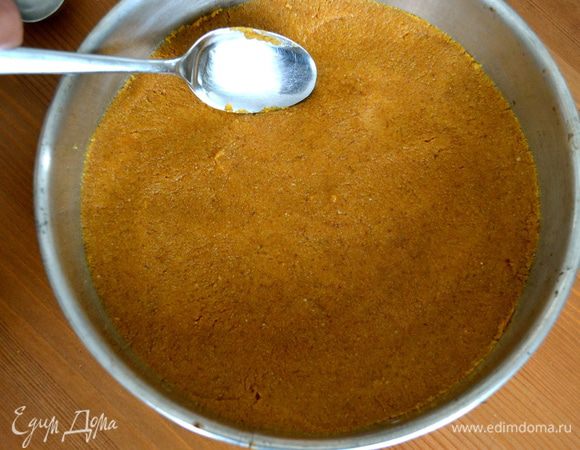 Полученную мокрую крошку пересыпать в подготовленную форму для выпечки со съемными бортиками (диаметр формы 24-25 см). Выложить дно формы и сформировать небольшой бортик. Поставить в холодильник на то время, пока мы будем заниматься приготовлением начинки из кремового сыра.