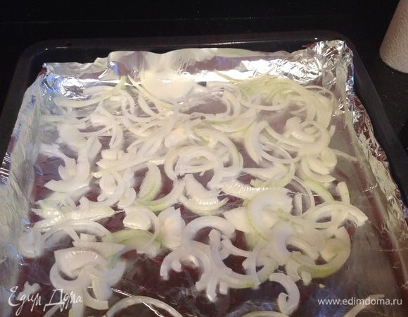 Противень застелить фольгой. Нарезать лук полукольцами. Выложить на противень.