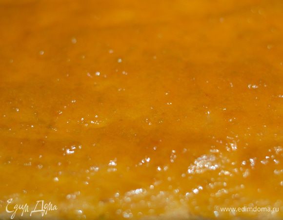 Разогреть джем, вынуть бисквит из духовки, сразу же вместе с пергаментом выложить его на полотенце и распределить джем по всему бисквитному коржу.