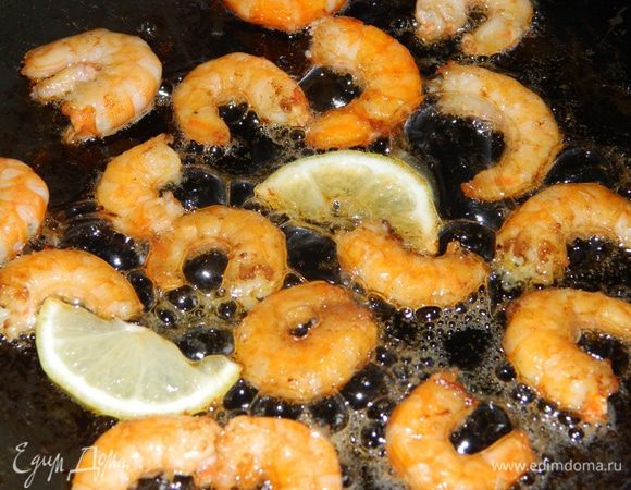 Очищенные креветки обжарить на растительном масле с дольками лимона.