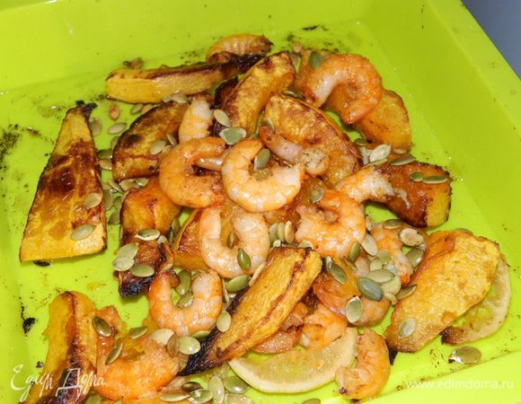 По истечении 20 минут достать тыкву из духовки, добавить креветки, тыквенные семечки, тертый чеснок, посолить, все сбрызнуть винным уксусом и соком лимона. Отправить в духовку еще на 10 минут.