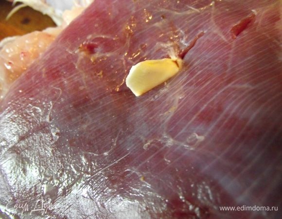 В надрезы положите небольшие кусочки холодного сливочного масла. Масло придаст индейке дополнительную сочность при запекании.