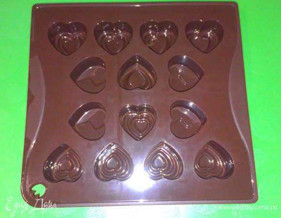 Вылейте трюфельную массу в форму (у меня силиконовая, в виде сердечек). Как альтернативу можно использовать обычную прямоугольную форму, предварительно застелив ее бумагой для выпечки.
Постучите формой об стол, чтобы убрать пузырьки воздуха.