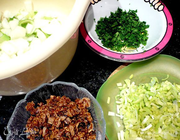 Для начала приготовим начинку. Порежем мелким кубиком инжир. Мелко порубим светлозеленую часть одного лука-порея. Мелко порубим петрушку. Для тушения мяса также порежем достаточно крупно весь остальной лук-порей и репчатый лук. Две морковки порубим также немелко. 