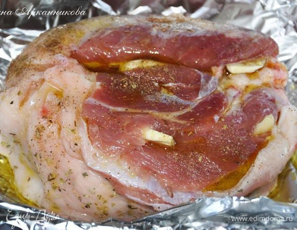 Свинину положить в фольгу. Обмазать травами, солью и перцем. Сделать надрезики и вставить дольки чеснока, порезанные вдоль. Полить маслом.  