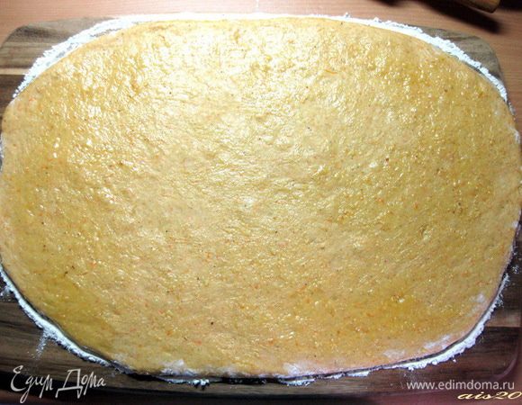 Когда тесто подойдет, выложить его на посыпанную мукой доску. Слегка припылить тесто мукой и раскатать скалкой в прямоугольник толщиной около 1 см.