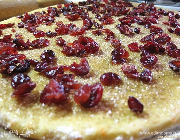 Смазать тесто растопленным сливочным маслом, посыпать сахаром с корицей и равномерно распределить клюкву.