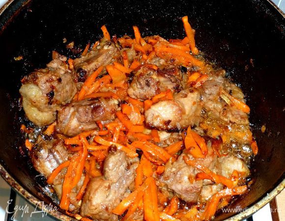 Добавляем, порезанную соломкой морковь.
 Жарим  до поджаристой корочки мяса .