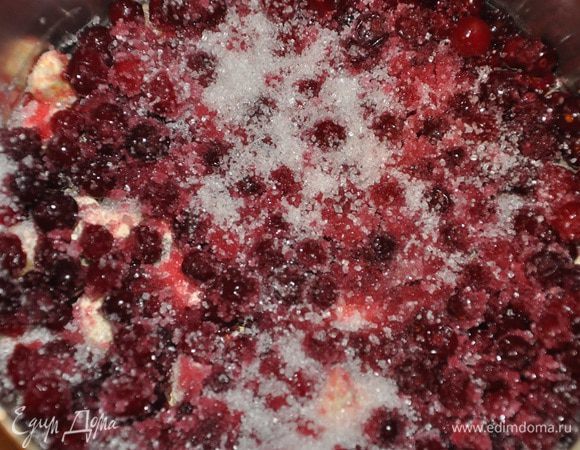 Форму для выпекания (у меня диаметром 23 см.) выстелить пекарской бумагой, смазать маслом края формы. На дно выложить сливочное масло, клюкву и сахар. 