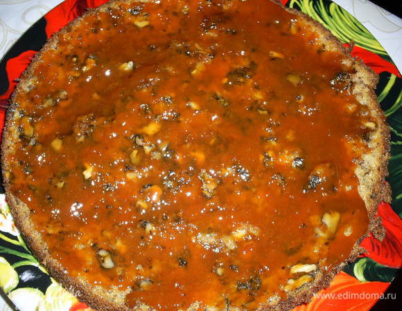 Приступаем к сборке торта. На блюдо выкладываем первый корж. Смазываем его половиной абрикосового джема. Примерно 2 полные столовые ложки.