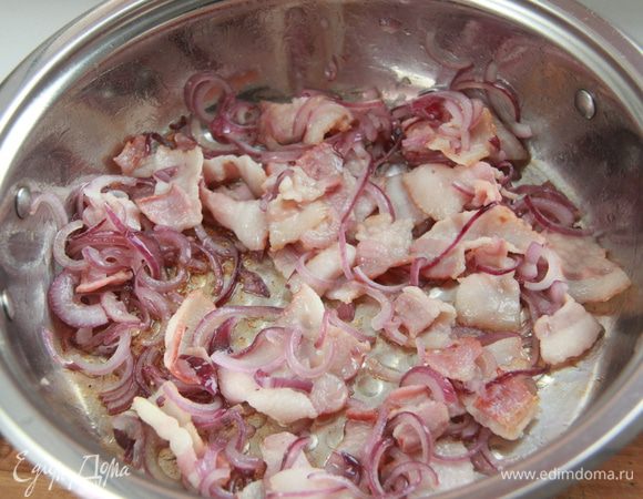 Красный лук нарезать полукольцами, бекон небольшими полосками. Обжарить всё на оливковом масле минут пять.